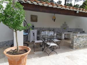 eine Terrasse mit einem Tisch, Stühlen und einem Baum in der Unterkunft VILLA LA LICORNE Piscine privée, Jacuzzi, Massages, Tennis, Golf à 9km in Belcodène