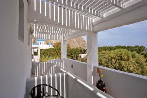 a white pergola with a table and chairs on a balcony at Sunrise Studios in Perissa in Perissa +10 photos