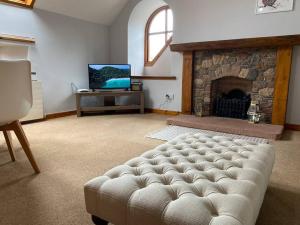 a living room with a couch in front of a fireplace at The Stables, charming converted, 2 bedroom Cottage, Melrose in Darnick