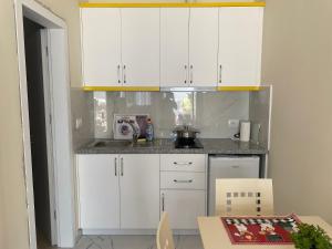 a small kitchen with white cabinets and a table at Gerard apartments in Sarandë