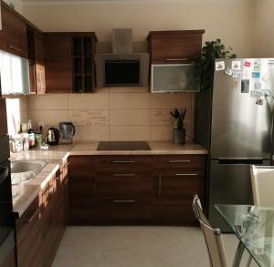 a kitchen with wooden cabinets and a stainless steel refrigerator at Apartament DINO in Ustka