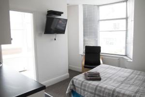 ein Schlafzimmer mit einem Bett, einem Stuhl und einem TV in der Unterkunft Bursar Street 21 in Cleethorpes