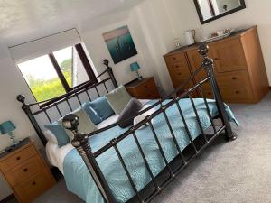 a bedroom with a metal bed with blue pillows at Meadowview Cottage, St Ives View in Camborne
