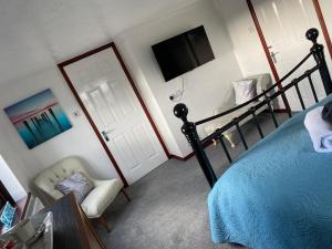 a bedroom with a bed and a tv and a chair at Meadowview Cottage, St Ives View in Camborne