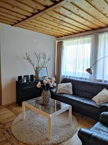 a living room with a black leather couch and a coffee table at Vila su sauna ir kubilu gamtos apsuptyje in Kalviškiai