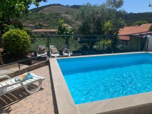 einen Pool mit einer Chaiselongue neben einem Haus in der Unterkunft Casa do Outeiro in Mondim de Basto
