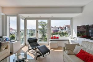 uma sala de estar com um sofá, cadeiras e janelas em Top location! Unique luxurious 2-bedroom apartment in Knokke - 't Zoute em Knokke-Heist