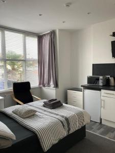 a bedroom with a bed with a chair and a microwave at The Gladson Guesthouse in Cleethorpes