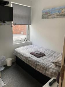 a bedroom with a bed and a window with a towel on it at The Gladson Guesthouse in Cleethorpes