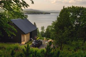 a black house with a car parked next to a lake at Duchesnay - Sepaq in Sainte-Catherine