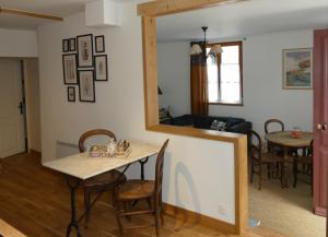 ein Esszimmer und ein Wohnzimmer mit einem Tisch und einem Spiegel in der Unterkunft Chez Elise et Thomas in Le Mage
