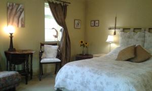 een slaapkamer met een bed, een stoel en een raam bij Thorpe Green House Vegetarian Bed & Breakfast in Robin Hood's Bay