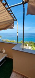 uma vista para o oceano a partir de uma varanda com um guarda-sol em Indipendent apartment with a spectacular view em Cala Gonone