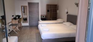 a small room with two beds and a desk at Hôtel Casa Mea in Bastia
