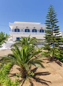 um edifício branco com uma palmeira em frente em Galini Studios em Maltezana