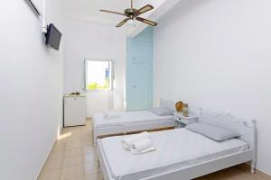 een kamer met 3 bedden en een plafondventilator bij Galini Studios in Maltezana