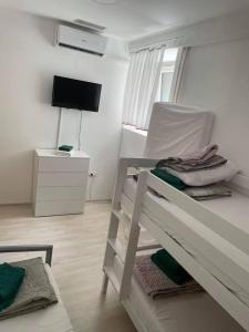ein weißes Schlafzimmer mit einem Etagenbett und einem TV in der Unterkunft Mediteran in Koper