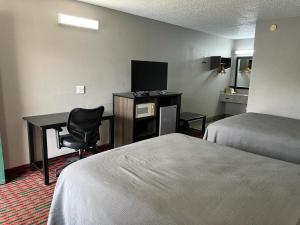 a hotel room with two beds and a desk at Keywest Inn - Tuscumbia - Muscle Shoals in Tuscumbia