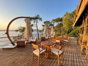 a deck with tables and chairs and an umbrella at Lov Faralya Adults Only in Faralya