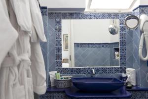 bagno blu con lavandino e specchio di Hotel Lisca Bianca a Panarea