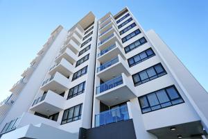 wysoki biały budynek apartamentowy z niebieskim niebem w tle w obiekcie Q Resorts Paddington w mieście Townsville