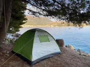Tenda verde e bianca seduta accanto a un lago di Pine Side Camp a Himare