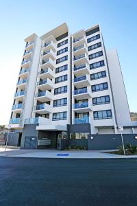 a large white apartment building with a parking lot at Q Resorts Paddington in Townsville