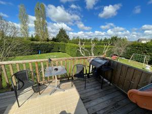 a deck with chairs and a table and a grill at Le Clos des Trois Provinces, Zoo de Beauval in Noyers-sur-Cher