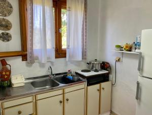 a small kitchen with a sink and a refrigerator at Pitsa's Rooms in Tsonia