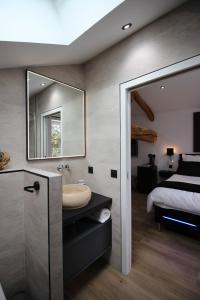 a bathroom with a sink and a bed and a mirror at Le grain de Louise in Lancié