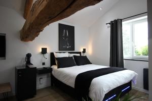 een slaapkamer met een zwart-wit bed en een raam bij Le grain de Louise in Corcelles-en-Beaujolais