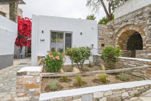 a white house with a stone wall and flowers at LE PETIT Ενα μικρό αλλά όμορφο σπίτι in Stení