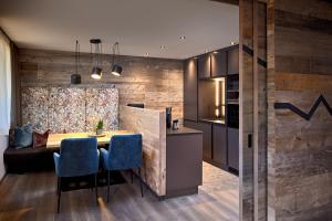 a kitchen and dining room with a table and blue chairs at Mei.Berg premium view Appartements in Saalbach Hinterglemm