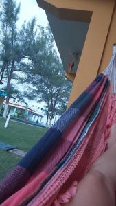 a person laying in a hammock looking out the window at Village em Condomínio c/ piscina e acesso a praia in Camaçari