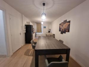 uma sala de jantar com uma mesa de madeira e cadeiras em Privée : Jacuzzi + sauna + billard + jeux SO em Saint-Quentin