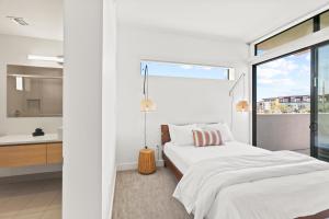 Dormitorio blanco con cama y ventana grande en Minnezona Apartments, en Scottsdale