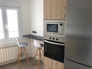 a kitchen with a microwave and two stools at ApartamentoValleTena9 in Sabiñánigo