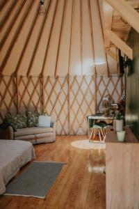 a room with a couch and a table in a yurt at Aloha Glamp - Domki z prywatnym jacuzzi & balia & sauna in Zagórnik