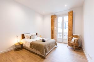 una camera bianca con un letto e una sedia di Lujo, comodidad y espacio Gijon centro a Gijón