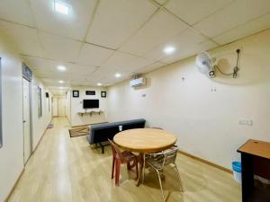 Pak Long Shoplot Homestay 2 في شاه عالم: غرفة بها طاولة وكراسي وأريكة