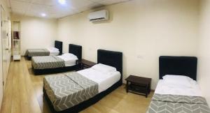 um quarto com três camas num quarto em Pak Long Shoplot Homestay 2 em Shah Alam