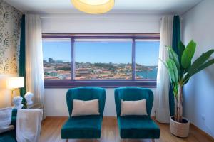 two green chairs in a room with a large window at 180º Porto River View in Vila Nova de Gaia