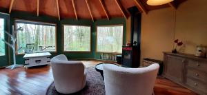 a living room with chairs and a table and windows at Woeste Hoogte - Groesbeek in Groesbeek