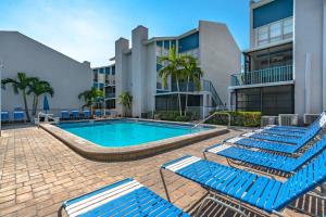 a swimming pool with blue lounge chairs in front of a building at Madeira Beach Yacht Club 215F, 2 Bedrooms, Pool Access, Spa, WiFi, Sleeps 6 in St. Pete Beach