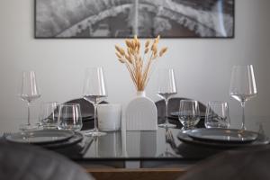 una mesa con platos y vasos y un jarrón con flores en Bheaven I Explorer Premium Apartment, en Bremerhaven