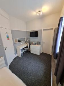 a small room with a desk and a tv at Queens Plaza Hotel in Blackpool