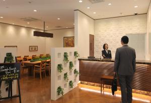 un hombre y una mujer parados en un mostrador en un restaurante en Odakyu Station Hotel Hon-Atsugi, en Atsugi