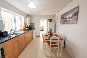 a kitchen with a sink and a table with chairs at Cheerful 4 bedrooms home 8 mn to train station in Plumstead