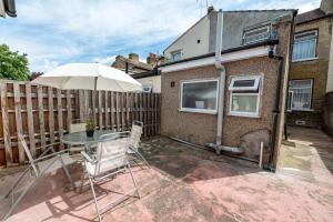 a patio with a table and an umbrella at Cheerful 4 bedrooms home 8 mn to train station in Plumstead
