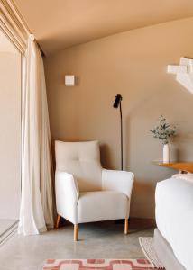 a living room with a white chair and a lamp at Immerso Hotel, a Member of Design Hotels in Ericeira